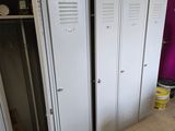 several white lockers are in a room with a pink wall