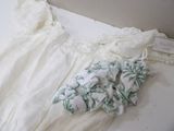 une robe blanche et une paire de mitaines posées sur un lit