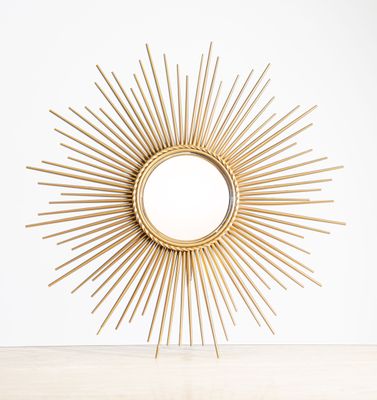 a gold sunburst mirror sitting on top of a wooden table
