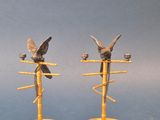 une paire de bougeoirs anciens en laiton surmontés d'oiseaux