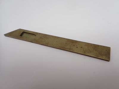 une plaque en laiton percée d'un petit trou au milieu
