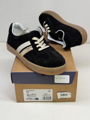 une paire de baskets noires et blanches posée sur une boîte en carton