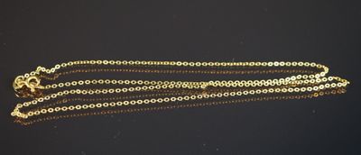 un gros plan d'un collier en or avec une chaîne, posé sur une surface noire