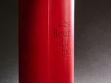un livre rouge posé sur une table, devant un fond noir