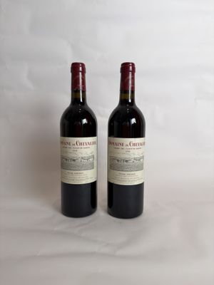 two bottles of red wine sitting on top of a white table