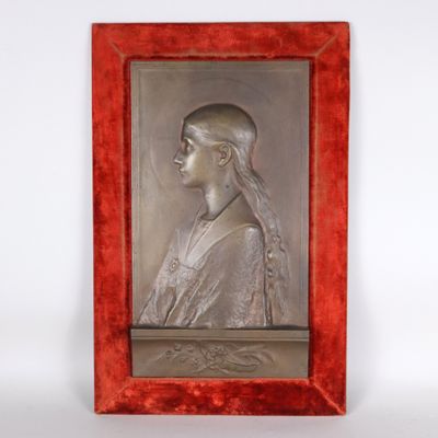 une plaque métallique représentant une femme, dans un cadre rouge sur fond blanc