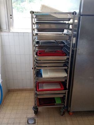 Plusieurs plateaux de nourriture sont empilés sur un chariot dans une cuisine