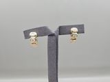 a pair of gold and diamond earrings on a stand
