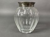a glass vase with a silver lid on a table