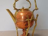a copper tea kettle on a stand on a table