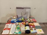 a box of sewing supplies on a table next to a sewing machine