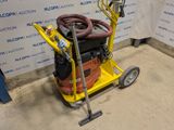 a yellow cart with a hose on it in front of a wall