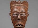 a close up of a wooden mask on a stick