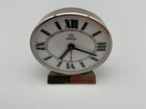 a small silver clock with roman numerals on it