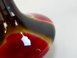 un vase rouge et noir posé sur une table blanche