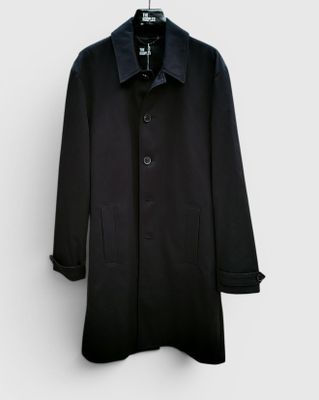 un manteau noir suspendu à un cintre devant un mur blanc