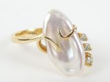 a close up of a pearl and diamond ring on a white surface