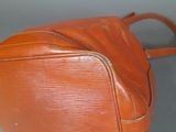 an orange leather bag with a zipper on the inside of it