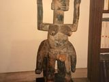 statue of a man holding a square object in a room with a bookcase