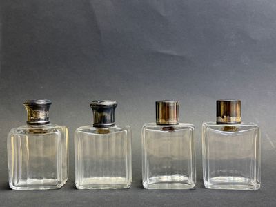 trois flacons de parfum sont alignés sur une surface grise