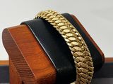 bracelet posé sur un présentoir en bois, sur lequel est posé un bracelet noir et doré