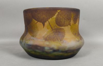 un vase en verre orné de feuilles, posé sur une table