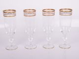 quatre verres à vin à bord doré posés sur une surface blanche