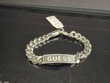 un bracelet en argent sur lequel est inscrit le mot « guess »