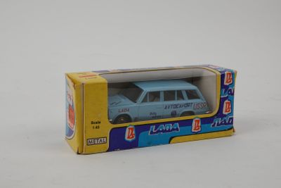 une petite voiture miniature dans une boîte posée sur une surface blanche