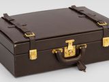 une valise marron posée sur une surface blanche