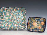 deux assiettes et un plateau orné de fleurs, posés sur une table