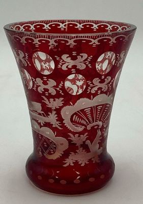 un vase rouge orné de motifs blancs, posé sur une table