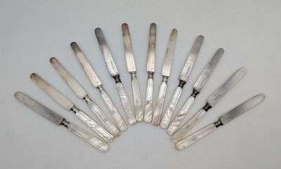 huit couteaux argentés disposés en cercle sur une surface blanche