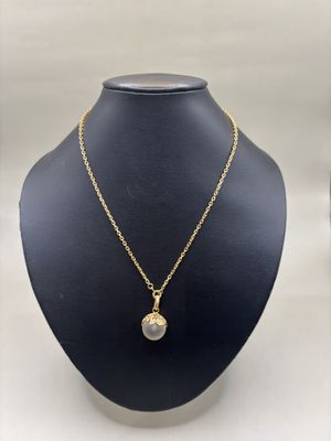 un collier plaqué or avec un pendentif rond, présenté sur un mannequin