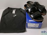 des sandales noires Birkenstock et un t-shirt posés sur une boîte