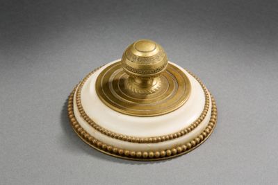 un objet blanc et doré posé sur une surface grise