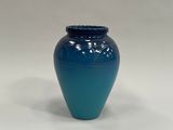 un vase bleu posé sur une surface blanche