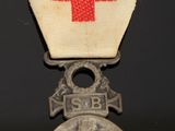 an old silver medal with a red cross on top of it