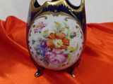 a small vase with flowers painted on it on an orange cloth