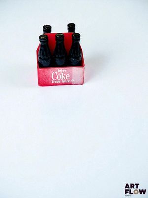 trois bouteilles de Coca-Cola dans une boîte rouge posée sur une surface blanche