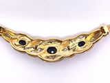 a close up of a gold necklace with blue stones on it