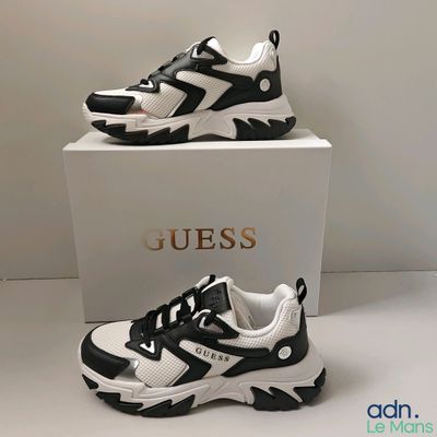 Deux paires de baskets noires et blanches sont exposées dans une boîte