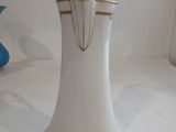 a white vase with a gold trim and a blue vase in the background