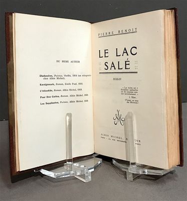un livre ouvert sur une table, à côté d'un bougeoir en verre