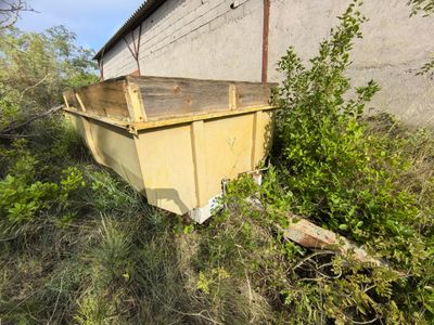 a yellow dumpster sitting in the grass next to a building