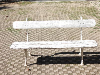 a white bench sitting on a cobblestone street