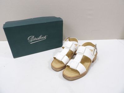 the white sandals are next to a green box on a white table