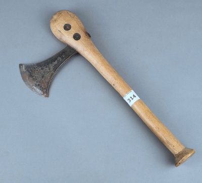 une vieille hache avec un manche en bois posée sur une surface grise