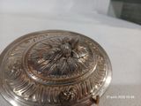 un plat en argent orné d'une fleur, posé sur une table