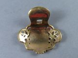 a gold brooch with a red stripe on it